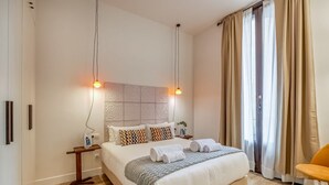 Een moderne hotelkamer met een groot bed, twee nachtkastjes en een stoel.