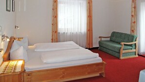A hotel room with a wooden bed, a green armchair, and a red carpet.