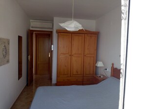Ein Schlafzimmer mit Bett, Holzschrank und Lampe.