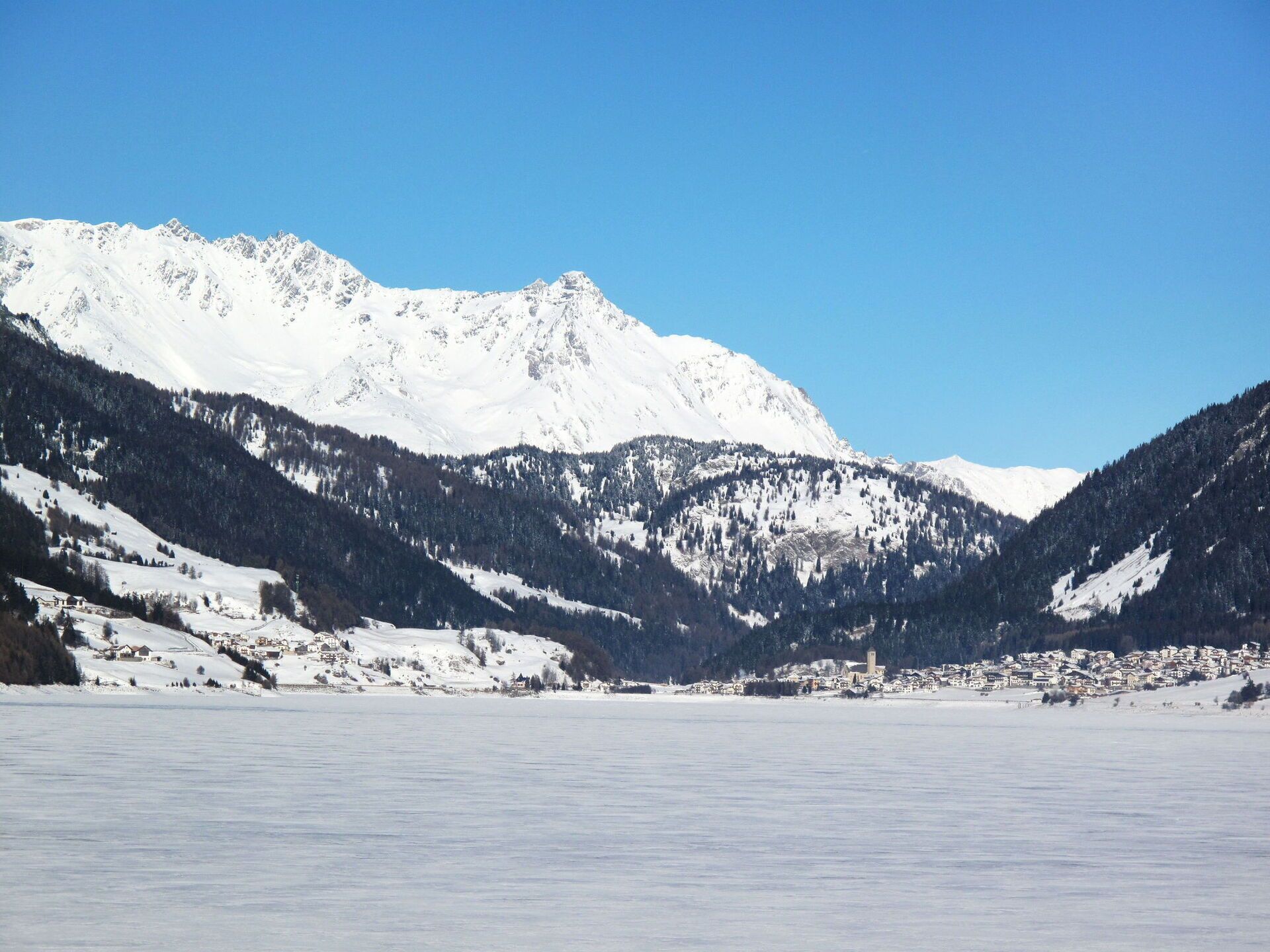 Paisatge de muntanya cobert de neu amb un poble a la vall.