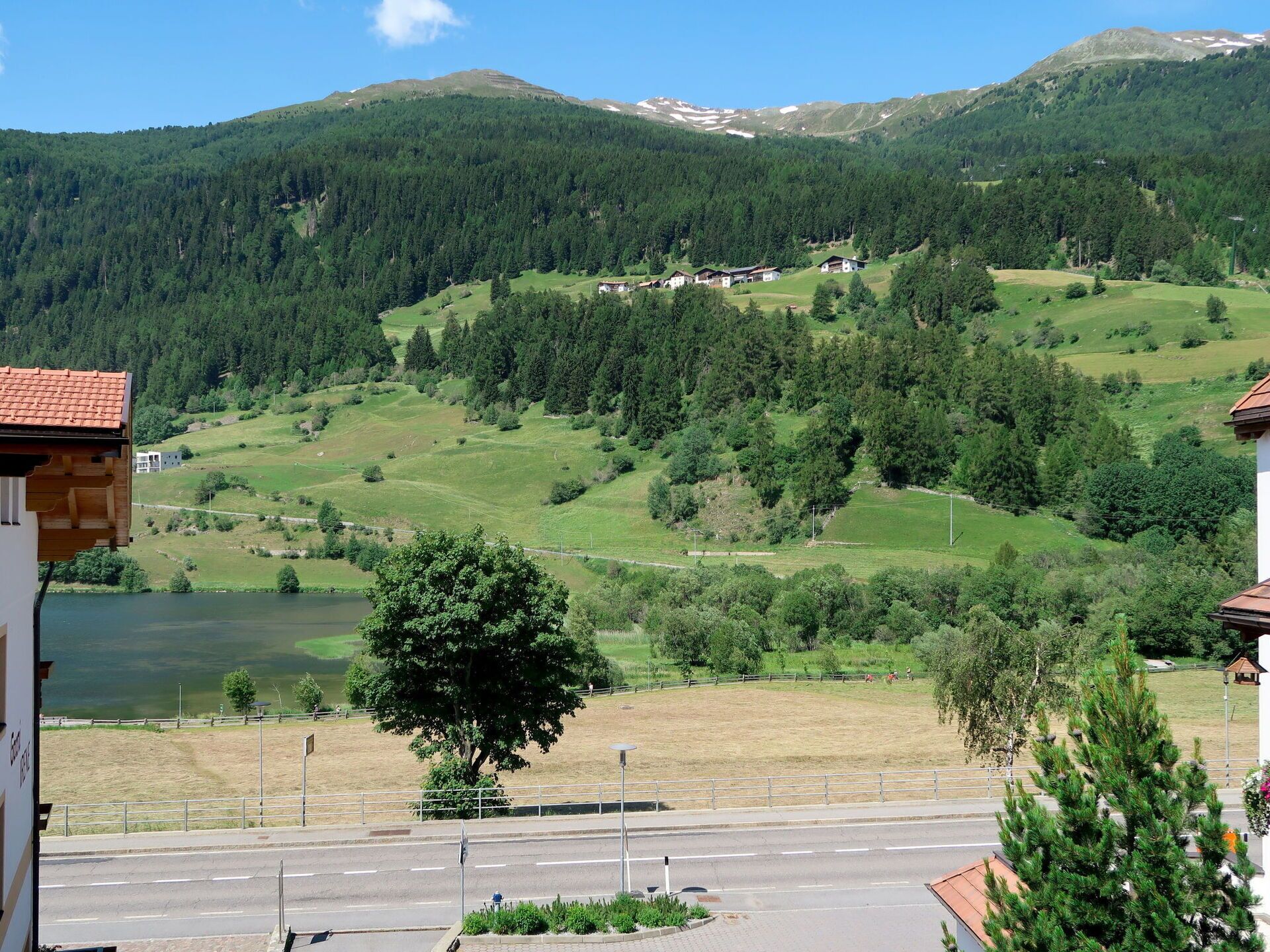 A view of a mountainous landscape with a lake, a road, and buildings in the foreground.