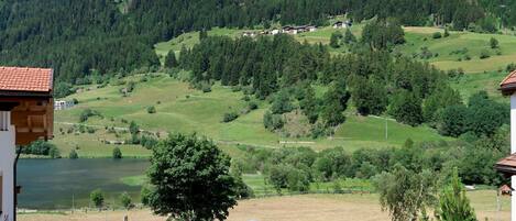 A view of a mountainous landscape with a lake, a road, and buildings in the foreground.