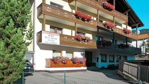 Ein mehrgeschossiges Gebäude mit Balkonen, die mit Blumenkästen geschmückt sind.