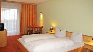 Een hotelkamer met een groot bed, een bureau met stoel, een tafeltje en een lamp.