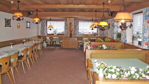 Un restaurante con mesas y bancos de madera, decoraciones florales y lámparas colgantes.