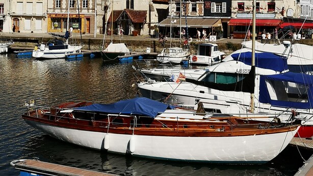 Un port amb vaixells amarrats, una església amb campanar i edificis amb botigues.