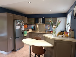 A modern kitchen with stainless steel appliances, a round dining table, and a variety of decorative items.