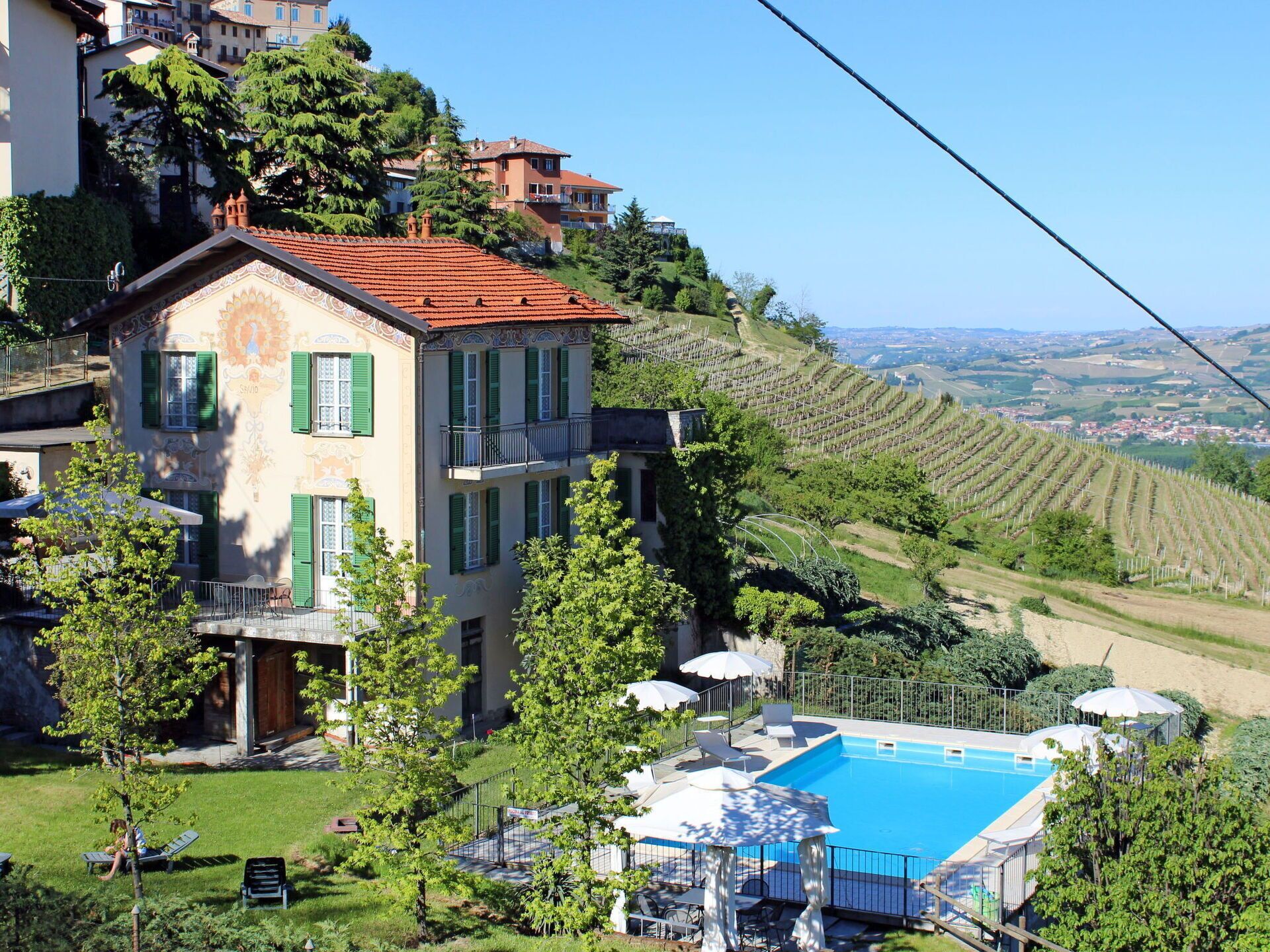 Una villa con piscina, circondata da rigogliosa vegetazione e vigneti.