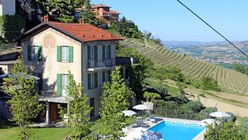 Una villa con piscina, circondata da rigogliosa vegetazione e vigneti.