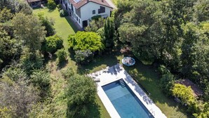 Une grande maison avec une piscine, entourée d’une végétation luxuriante.