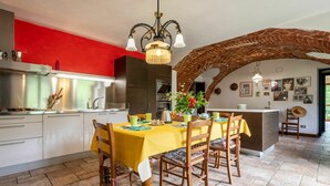 Un coin repas avec une table jaune, des chaises en bois et un mur d’accent rouge.