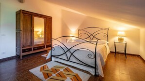 A bedroom with a bed, a wardrobe, a bedside table with a lamp, and a patterned rug. - Nice apartment for 4 people with WIFI, A/C, pool, TV and patio (Castagnole Delle Lanze)