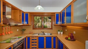 Eine Küche mit Holzausstattung, einer Edelstahlspüle und einem Fenster mit Blick ins Grüne.