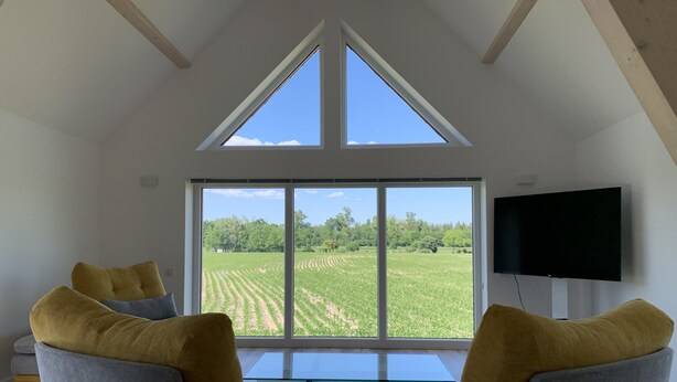 A modern living room with a large window, a flat-screen TV, and a sofa with yellow cushions.