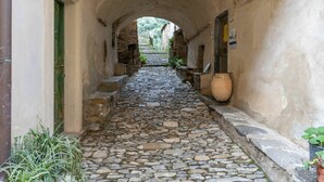 Un estrecho callejón empedrado con techos abovedados, escaleras de piedra y macetas con plantas.