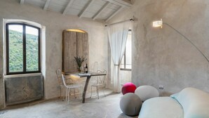 Una habitación rústica con una mesa y sillas de madera, un ventanal con vistas a la vegetación y una lámpara moderna.