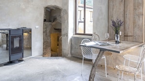 A rustic dining area with a stone wall, a wooden cabinet, and a window overlooking a street. - Nice apartment for 7 people with WIFI and terrace (Pietrabruna)