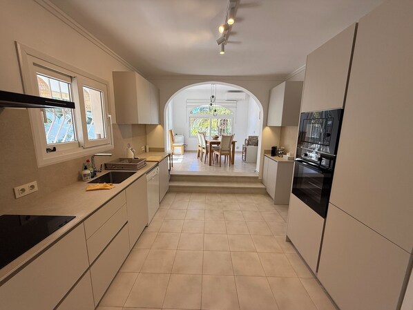 A modern kitchen with a central island, built-in appliances, and large windows. - Charming villa for 8 people in a quiet location, with large swimming pool and magnificent view (Benitachell)