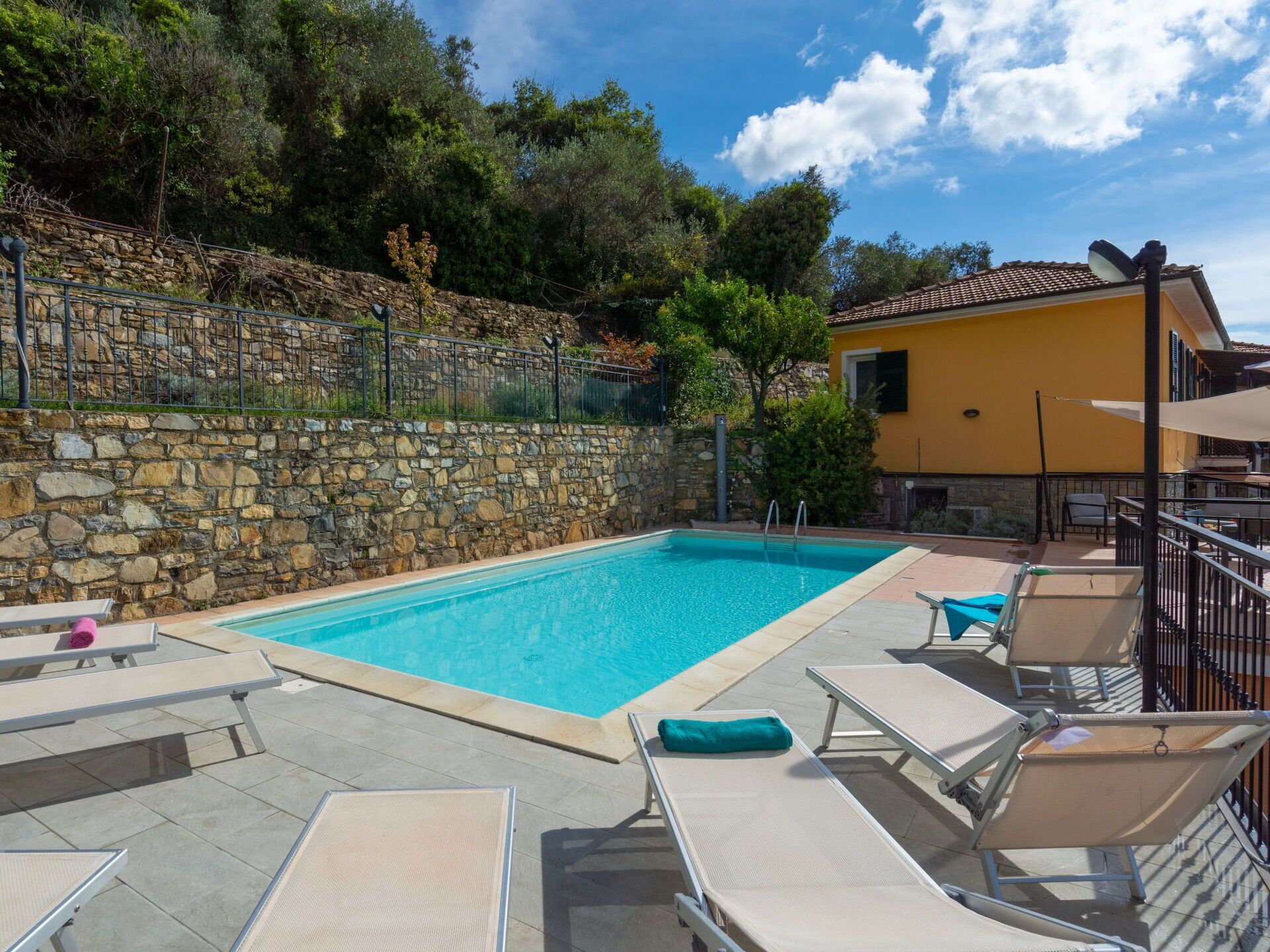 A swimming pool with lounge chairs and a stone wall.