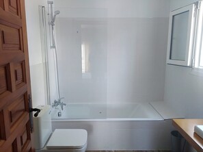 Een bad/douchecombinatie, een haardroger, een bidet, handdoeken