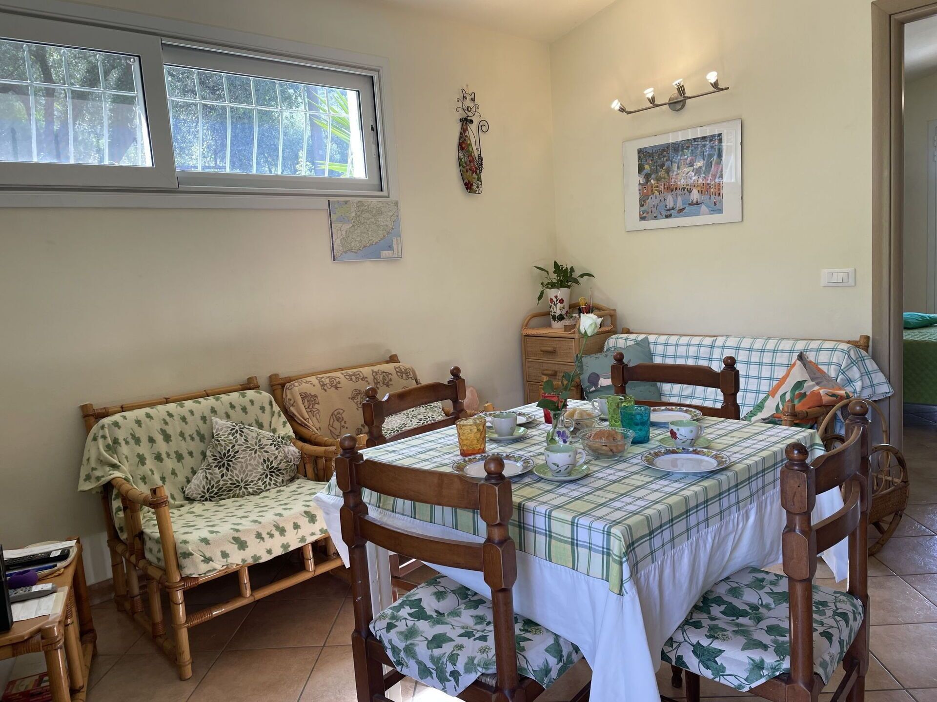 Un coin repas chaleureux avec une table en bois dressée pour quatre personnes, entourée de meubles en osier.