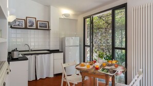 Una cucina moderna con mobili bianchi, un piano di lavoro nero e un'ampia finestra vista alberi.