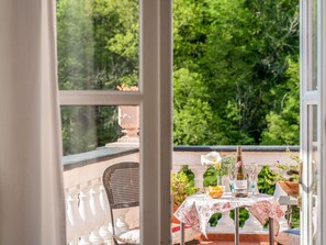 A balcony with a table set for dining, a chair, and a view of lush greenery. - Beautiful apartment for 9 guests with TV, patio and pets allowed (Dolcedo)