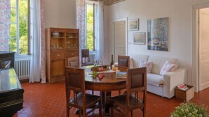 Zona pranzo con tavolo e sedie in legno, un mobiletto per il buffet e un divano bianco.