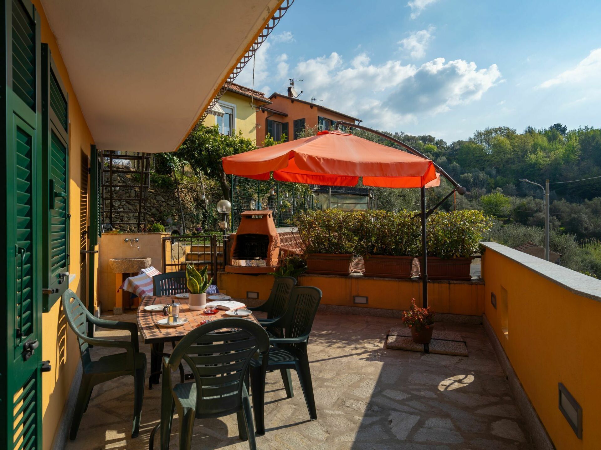 A patio with a table, chairs, and a red umbrella.