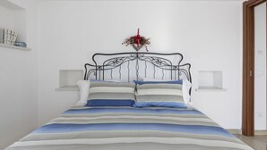 A neatly arranged bedroom with a bed, bedside tables, and a wall-mounted decoration. - Cosy apartment for 6 guests with A/C, WIFI, TV, terrace and pets allowed (Castellaro)