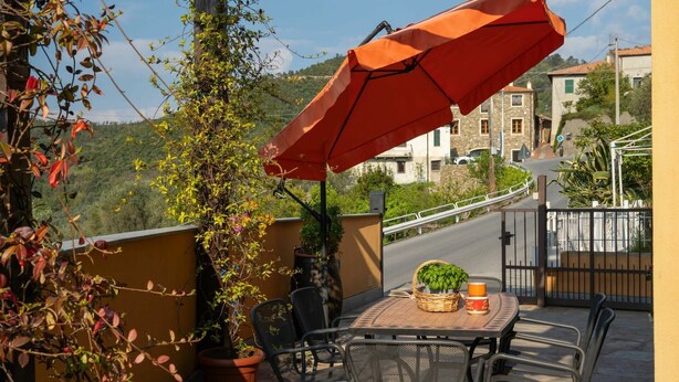 A terrace with a table, chairs, and an umbrella. - Cosy apartment for 6 guests with A/C, WIFI, TV, terrace and pets allowed (Castellaro)