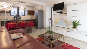 A modern living room with a red sofa, a glass coffee table, and a flat-screen TV mounted on the wall. - Cosy apartment for 6 guests with A/C, WIFI, TV, terrace and pets allowed (Castellaro)