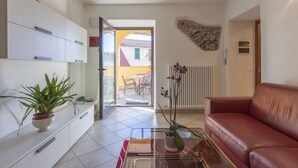 A modern living room with a glass coffee table, a red leather sofa, and a potted plant. - Cosy apartment for 6 guests with A/C, WIFI, TV, terrace and pets allowed (Castellaro)