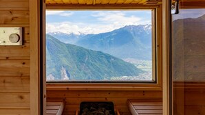 Una cabaña de madera con un amplio ventanal que ofrece vistas a un paisaje montañoso.