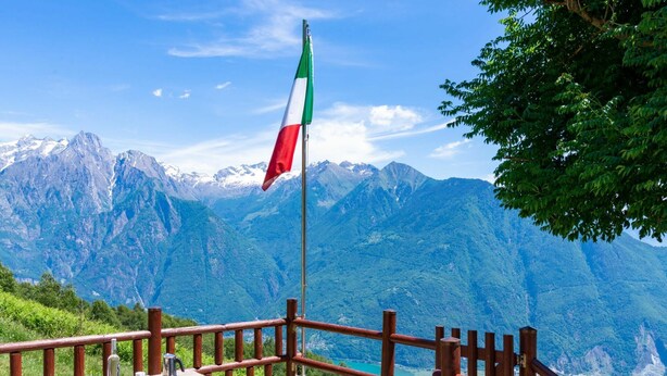 Un banco y una mesa de madera con una bandera, con vistas a un paisaje montañoso.