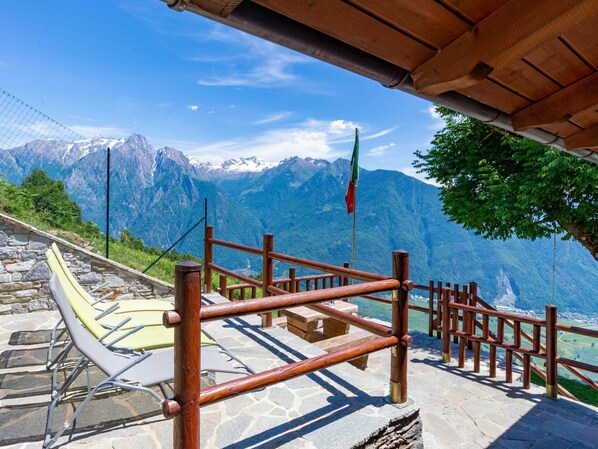 A stone staircase leading to a viewing platform with a wooden railing, overlooking a mountainous landscape.