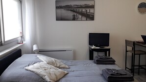 A bedroom with a bed, a desk, a chair, a television, and a window. - Studio Casa Marina in Sainte Cécile Plage (Sainte-Cécile Plage)