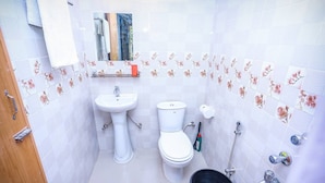 Ein kleines Badezimmer mit einem weißen Waschbecken, einer Toilette und einem Eimer.
