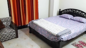 Ein Schlafzimmer mit einem Bett, einem Sessel und Vorhängen.