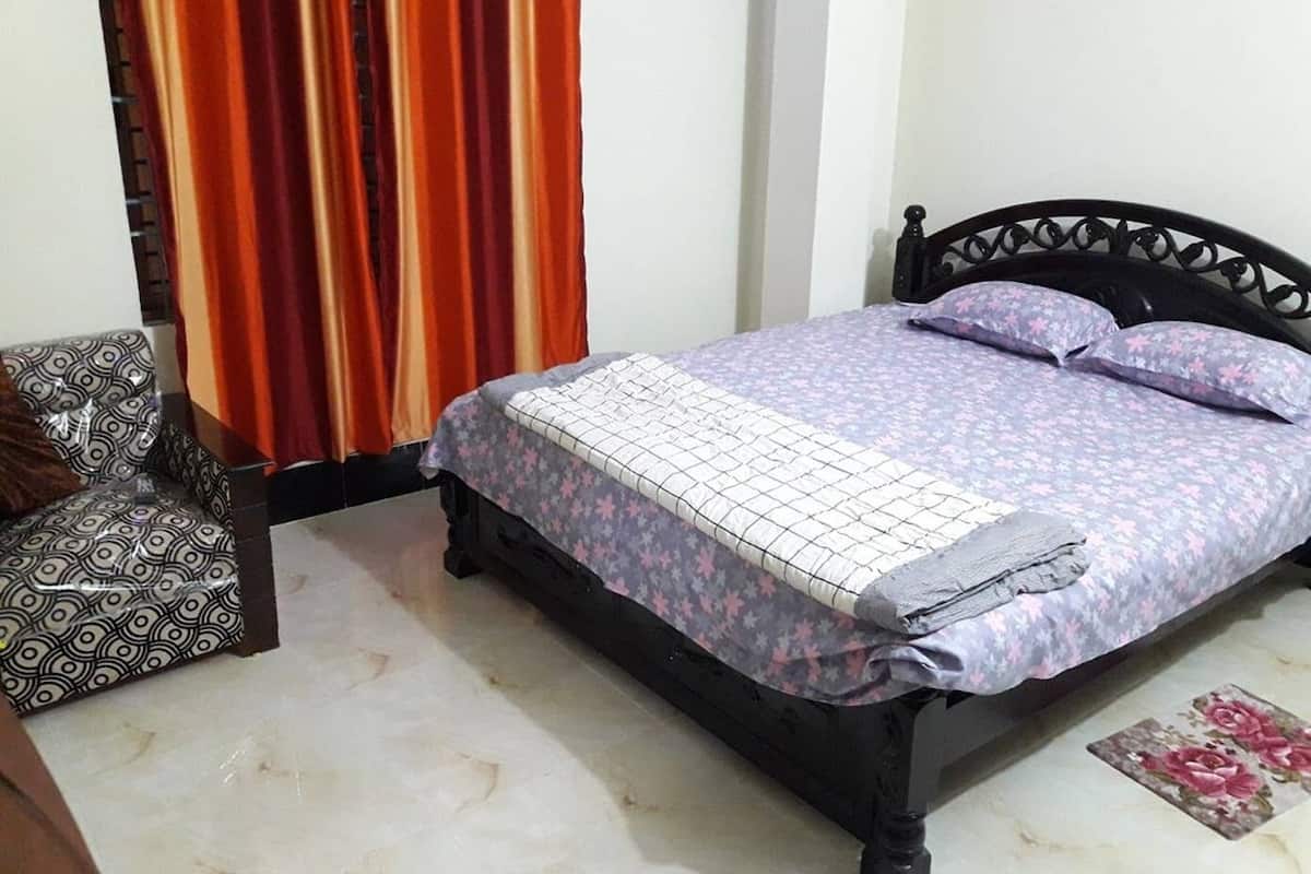 Un dormitorio con cama, una silla y cortinas.