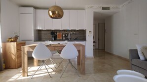 Una cocina moderna con armarios blancos, una mesa de comedor de madera y dos sillas blancas.
