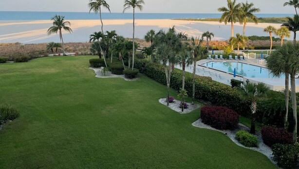 Une pelouse bien entretenue, une piscine et une vue sur la plage.