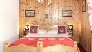 Ein schlächlich eingerichtetes Schlafzimmer mit einem Bett, herzförmigen Kissen und gerahmten Bildern an der Wand.