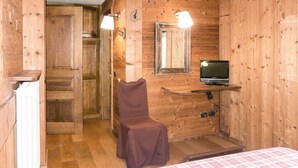Une pièce de style cabane en bois, comprenant un lit, une chaise, un téléviseur et un miroir.