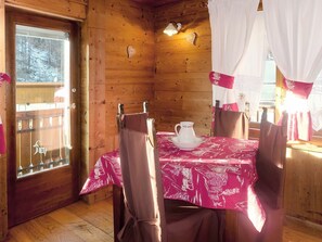 A wooden cabin interior with a dining table set for two, a white pitcher on the table, and a view of a snowy forest through a window. - Lovely apartment for 4 people with WIFI, TV, terrace and pets allowed (Paquier)
