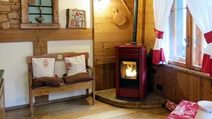 Une pièce chaleureuse avec un banc en bois, un mur en pierre, une cheminée et une fenêtre avec des rideaux.