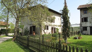 Ein rustikales Steinhaus mit weißer Fassade, einem Holzzaun und einem gepflegten Rasen.