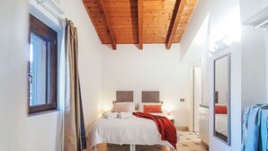 Een slaapkamer met een bed, nachtkastjes, een raam, een spiegel en een houten plafond.