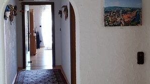 A hallway with a wooden floor, a rug, and a ceiling with a floral light fixture. There are two paintings on the wall depicting landscapes. - Großzügige Ferienwohnung in der Schlössergemeinde Küps (Küps - Tüschnitz)