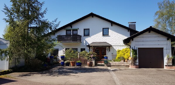 Ein zweistöckiges Haus mit Balkon, Garage und Auffahrt.